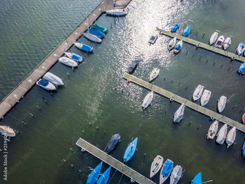 Aerial view of yacht marina on lake in Switzerland. Pier with boats parked near shore on jetty.