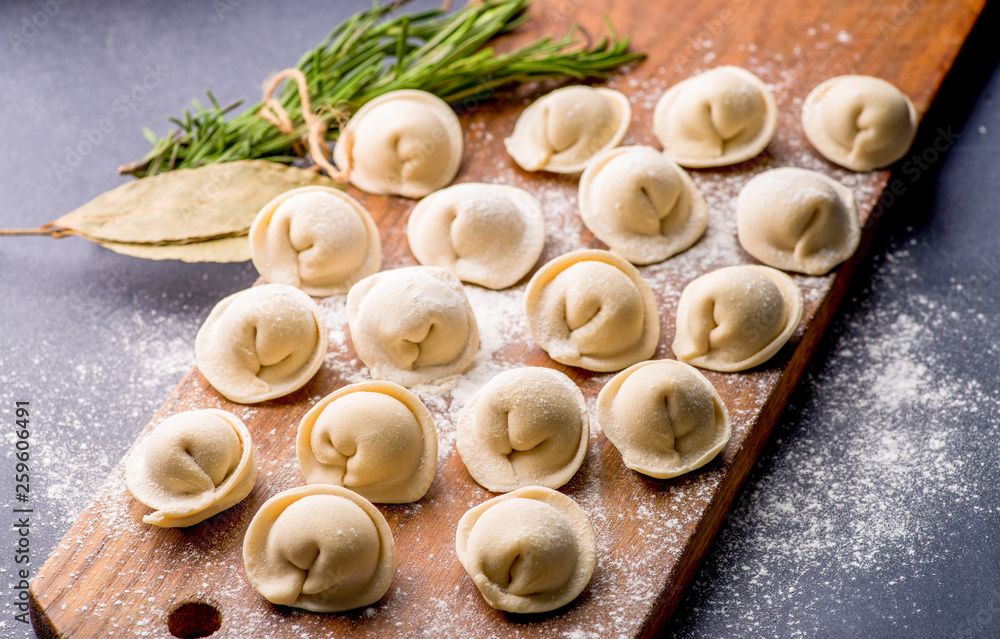 frozen khinkali and dumplings on a dark background with ingredients and spices. Semi-finished products frozen khinkali and dumplings on a dark background with ingredients and spices. Semi-finished products