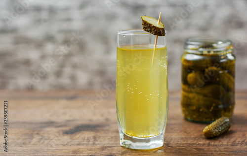 Bild auf Leinwand Pickle juice in glass and a can of pickled cucumbers on wooden table background