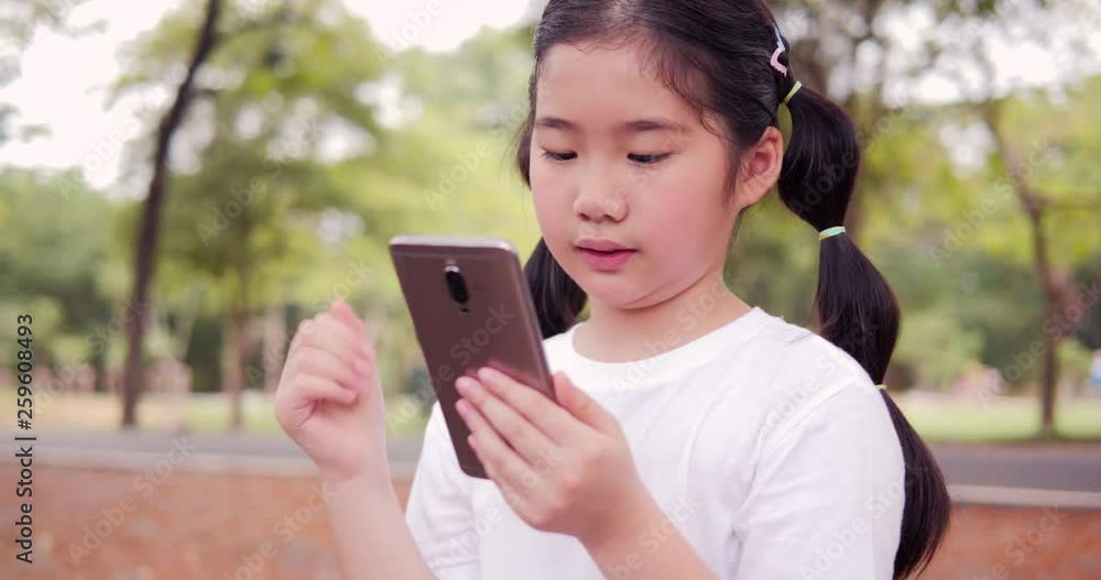 Asian little girl using smartphone at park. Technology and Education concept. Asian little girl using smartphone at park. Technology and Education concept.