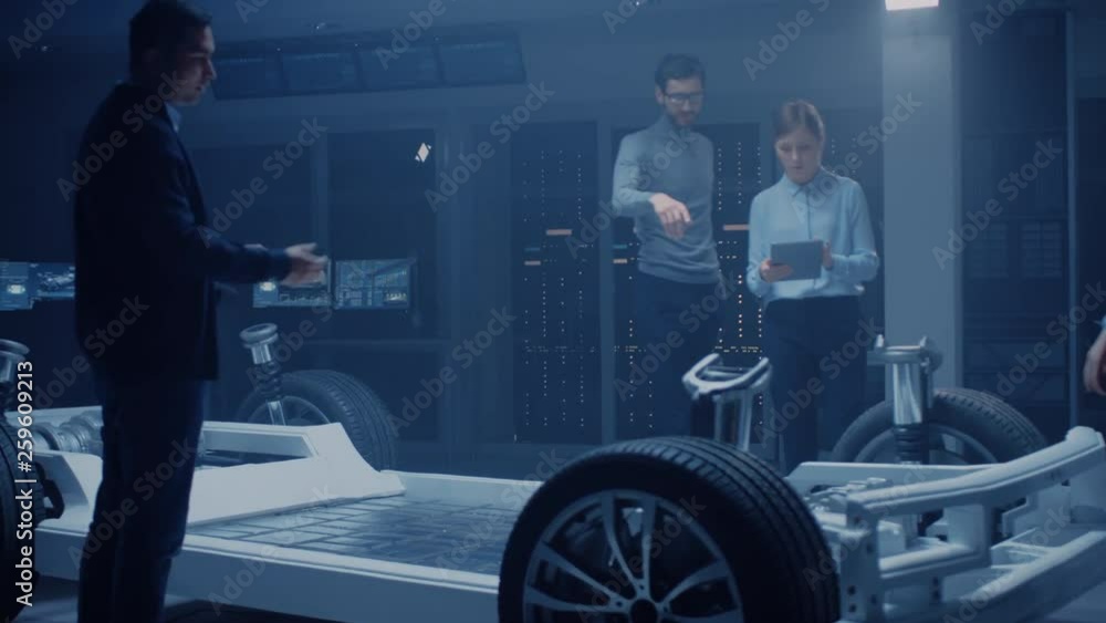 Automobile Engineer Working on Electric Car Chassis Platform, Using Tablet Computer Augmented Reality with 3D CAD Software Modelling. Innovative Facility: Vehicle Frame with Wheels, Engine, Battery Automobile Engineer Working on Electric Car Chassis Platform, Using Tablet Computer Augmented Reality with 3D CAD Software Modelling. Innovative Facility: Vehicle Frame with Wheels, Engine, Battery