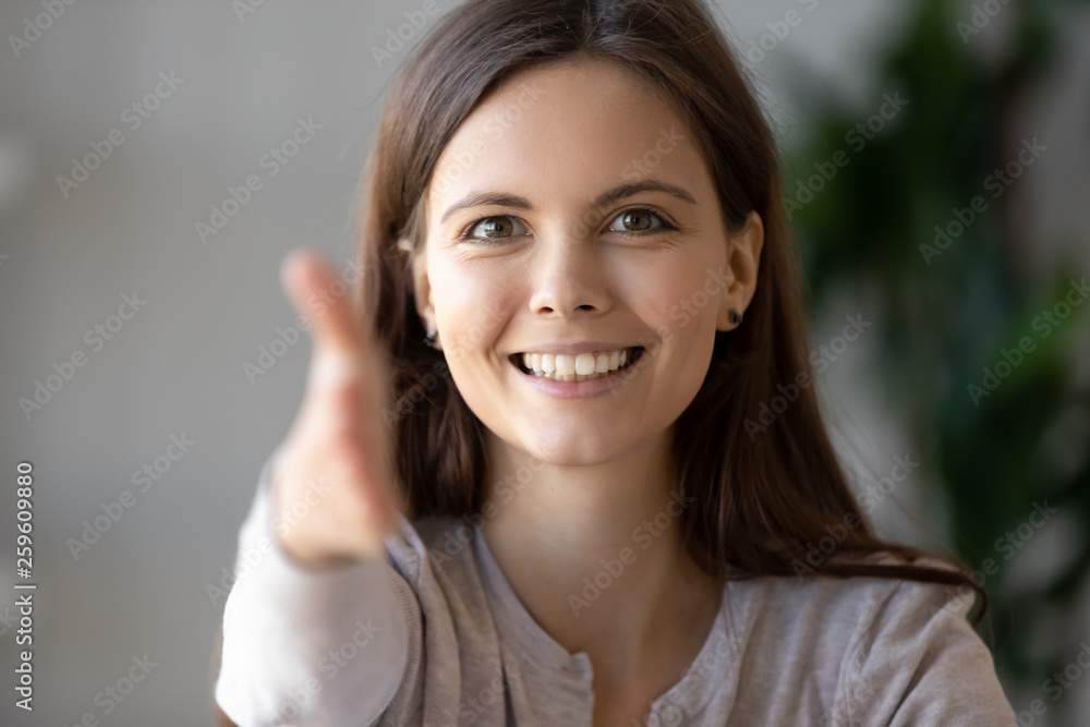 Young businesswoman holds out her hand to camera for handshake Young businesswoman holds out her hand to camera for handshake