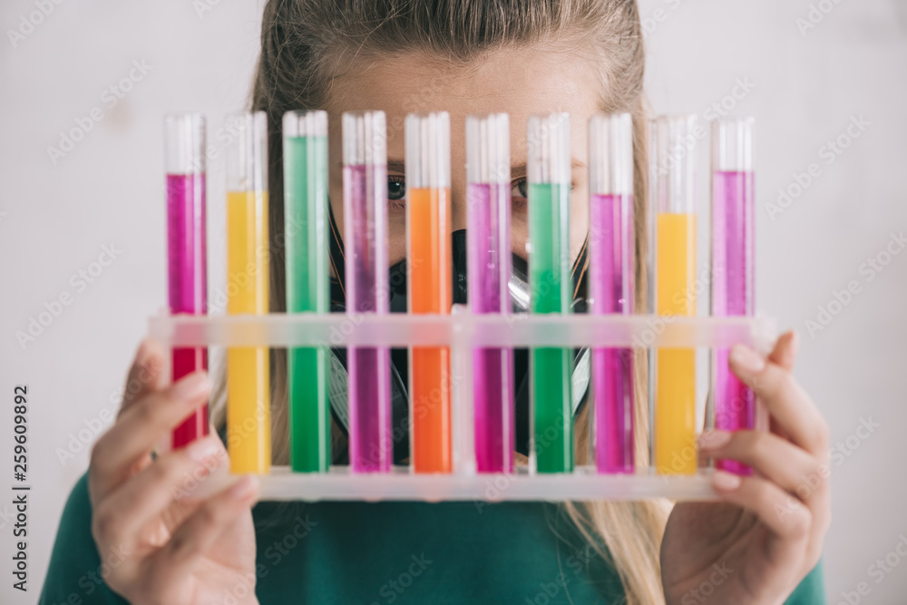 woman holding glass and colorful test tubes woman holding glass and colorful test tubes