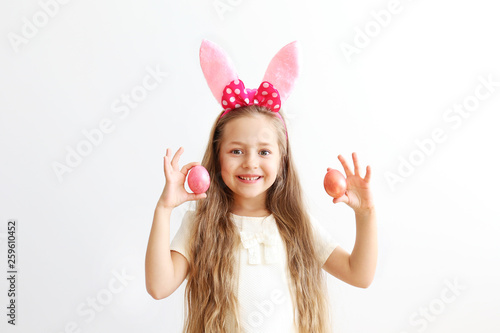 Portrait of cute little five year old girl with long blond hair wearing easter bunny ears with pink polka dot bow, smiling and having fun on holy day. Isolated white backgroung, copy space, close up.