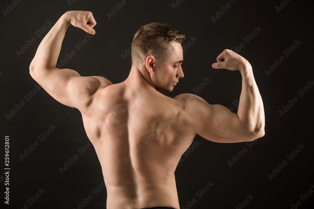 handsome muscular man on black background showing biceps