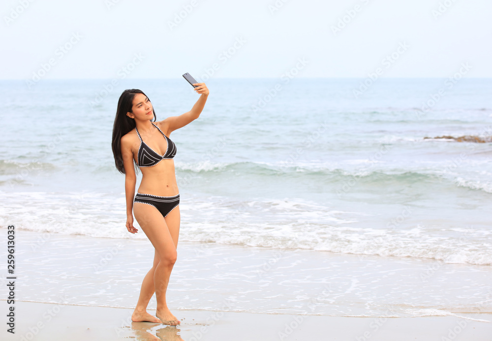 sexy and slim Asia woman with bikini do Selfie on beach by her mobile phone sexy and slim Asia woman with bikini do Selfie on beach by her mobile phone