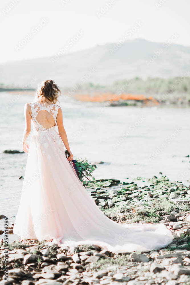 Beautiful fashion bride in wedding dress posing near river Beautiful fashion bride in wedding dress posing near river