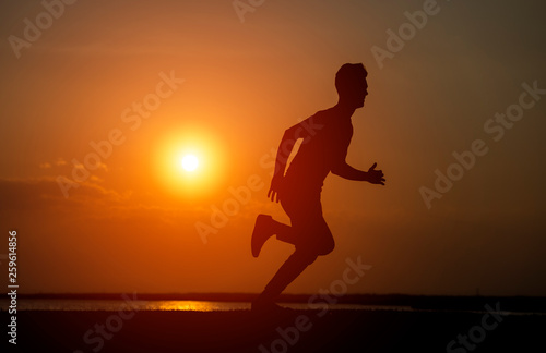 Fototapeta Naklejka Na Ścianę i Meble -  Silhouette of the running boy at sunrise.