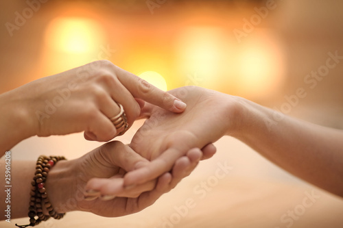 Chiromancer reading lines on woman's palm at table, closeup photo