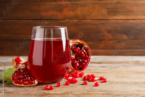 Tableau sur toile Glass of pomegranate juice and fresh fruits on table against wooden background,