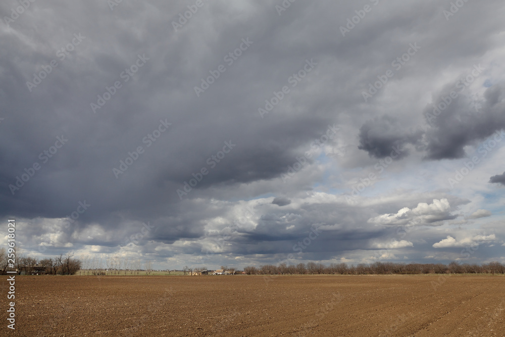 Agriculture, cultivated field with dark clouds in spring Agriculture, cultivated field with dark clouds in spring
