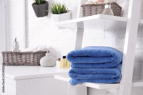 Stack of fresh towels on shelf in bathroom. Space for text
