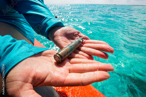 A bullet shell casing from World War II and the famed battle is found on a snorkel trip. Midway Atoll National Wildlife Refuge and Battle of Midway National Memorial, part of Papah?naumoku?kea Marine National Monument. Located in the northwest Hawaiian Islands, though not part of the state of Hawaii.    photo