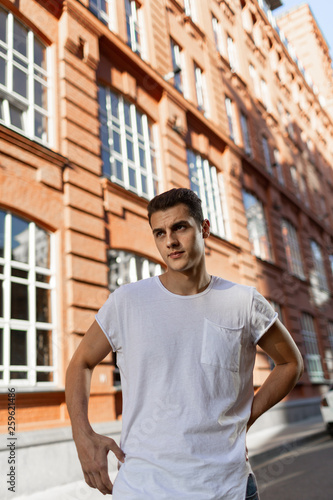 Beautiful caucasian man in white t-shirt and blue jeans stay on the street 
