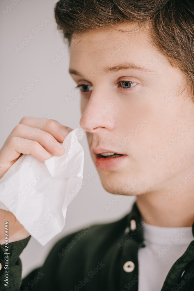 close up of sick handsome man having allergy and holding tissue close up of sick handsome man having allergy and holding tissue