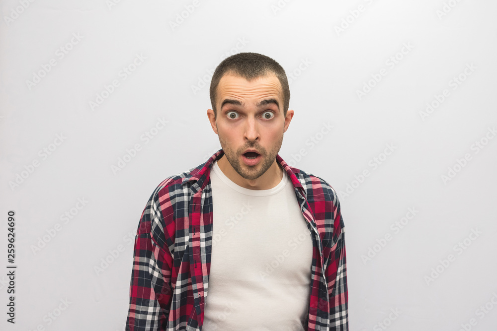 Attractive guy in plaid shirt having opened a mouth from shock, looking at camera, front view, white background with copy space, for advertising Attractive guy in plaid shirt having opened a mouth from shock, looking at camera, front view, white background with copy space, for advertising
