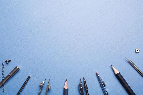 Compasses next to the pencils are laid out on a blue background photo