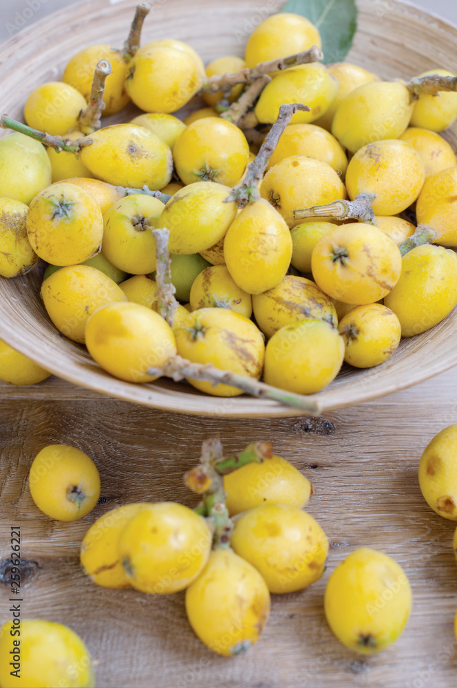 The vertical photo of asian fruit, loquat with the twigs on the wooden background