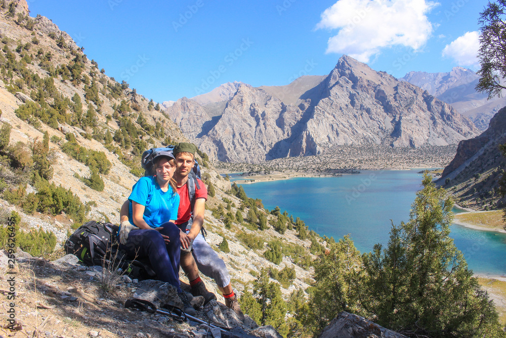 Young couple in the Fann mountains against the blue mountain lake