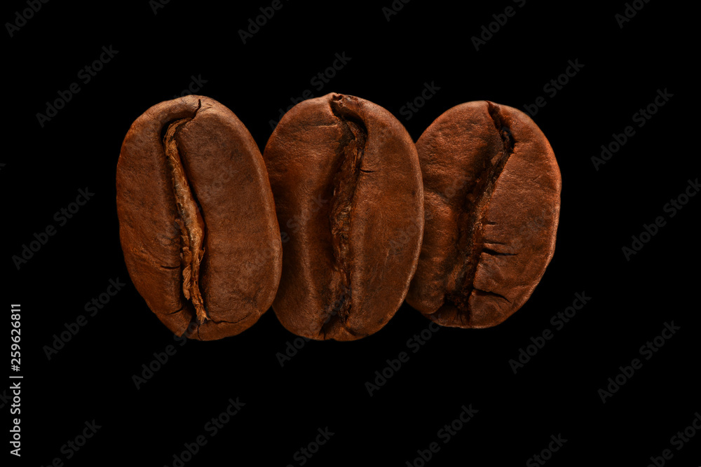 Three fresh roasted coffee beans isolated on a black background. Close up, macro. Post card, banner. Three fresh roasted coffee beans isolated on a black background. Close up, macro. Post card, banner.