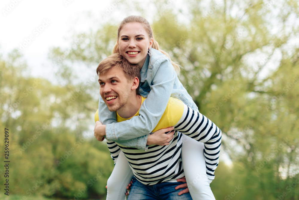 young beautiful girl on the back of a young man outdoors in summer 1 young beautiful girl on the back of a young man outdoors in summer 1