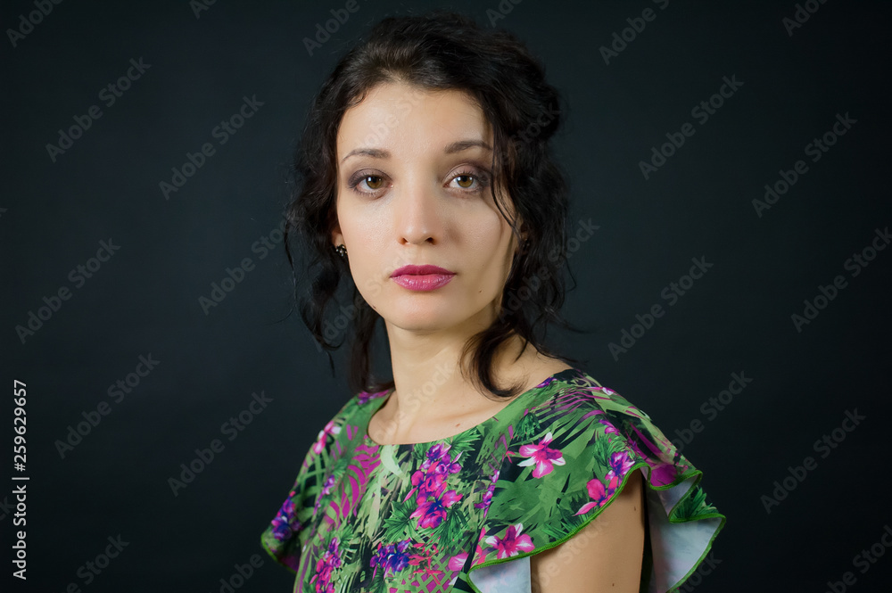 Young girl with sensual pink lips wearing green dress with flowers posing in studio on black background Young girl with sensual pink lips wearing green dress with flowers posing in studio on black background