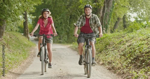 Romantic active couple riding e-bike bicycles mtb on a beutiful outdoor woods path.Wide shot.Friends italian trip in Umbria.4k slow motion