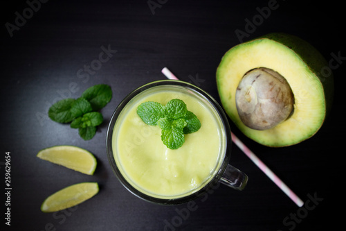 Avocado smoothie with lime and mint on black background. Top view with selective focus.