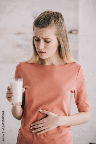 attractive woman with lactose intolerance looking at glass of milk photo