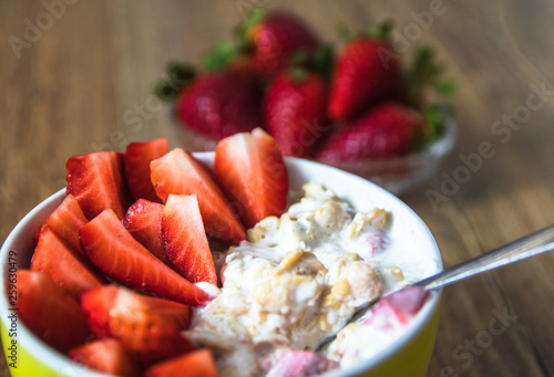 Fresh organic strawberries with muesli porridge in a yellow clay bowl