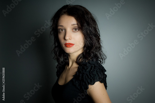 Studio portrait of sexy brunette woman with red sensual lips looking at the camera posing on black background