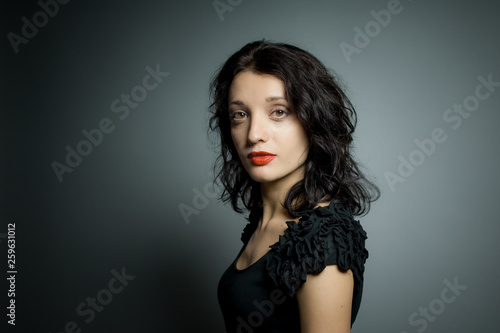 Studio portrait of sexy brunette woman with red sensual lips looking at the camera posing on black background