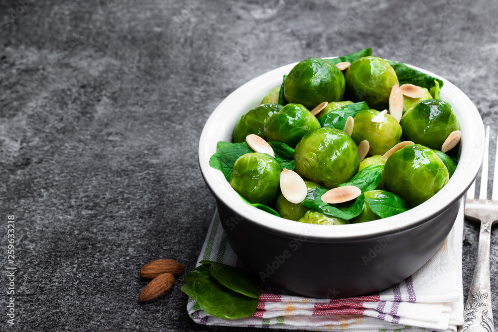 Cooked brussels sprouts with spinach and almonds on gray table Cooked brussels sprouts with spinach and almonds on gray table
