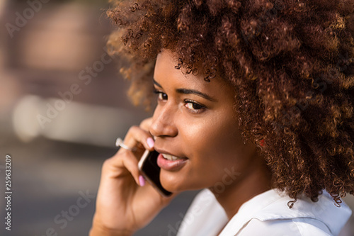Outdoor portrait of a Young black African American young woman speaking on mobile phone