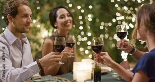 Four people, two couples happy talking and toasting with red wine during a romantic gourmet dinner or lunch. portrait medium shot.Friends italian trip in Umbria.4k slow motion