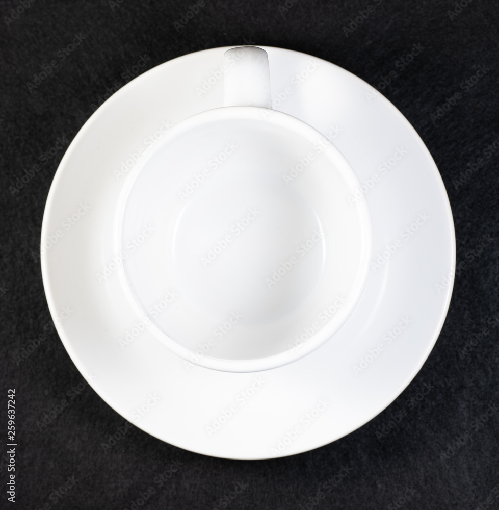 Coffee and cream pouring into a white cup on a white saucer with a black background Coffee and cream pouring into a white cup on a white saucer with a black background