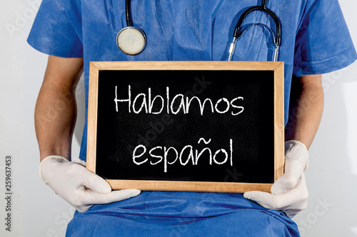 Doctor shows information on blackboard: we speak spanish.  Medical concept.