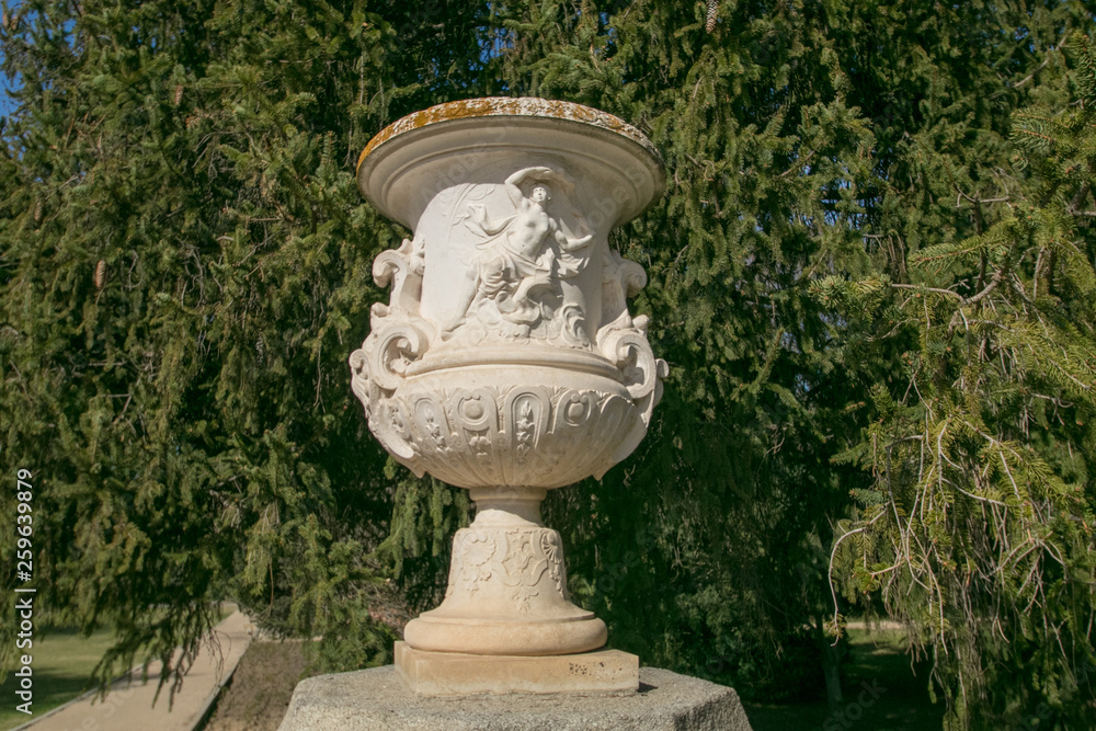 Roman Stone vase in the old classical style with trees in the Campo del Moro park, Madrid Roman Stone vase in the old classical style with trees in the Campo del Moro park, Madrid