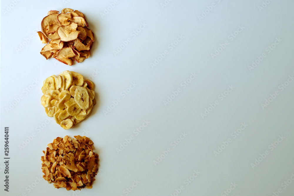 Obraz premium Healty organic chips on white background. Dehydrated banana, apple and coconut chips, top view.
