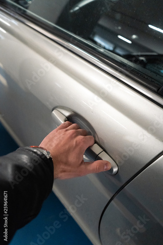 Closeup a men's hand on the latch of a car door opening it up - Light color car