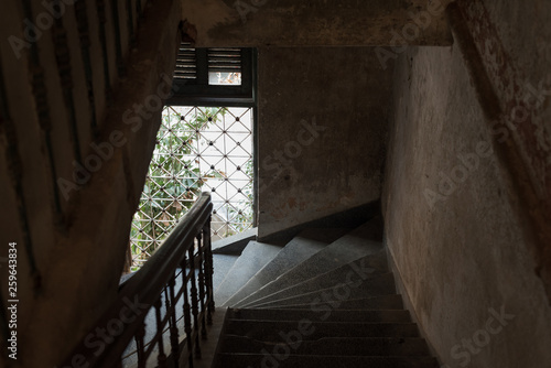 Dark stair descent in an old house with natural light coming from a barred window. The Mansion or Villa Bodega  Phnom Penh  Cambodia.