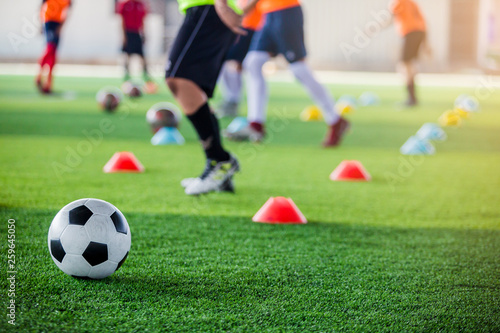 Soccer ball on green artificial turf with blurry of maker cones and player training © Koonsiri