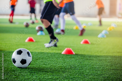 Soccer ball on green artificial turf with blurry of maker cones and player training