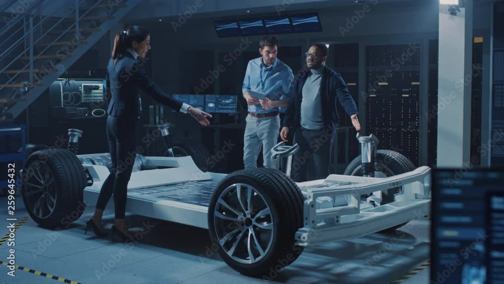 Automotive Innovation Facility: Team of Automobile Design Engineers Working on Electric Car Platform Chassis Prototype that Includes Wheels, Engine and Battery. Screens Show 3D CAD Software Automotive Innovation Facility: Team of Automobile Design Engineers Working on Electric Car Platform Chassis Prototype that Includes Wheels, Engine and Battery. Screens Show 3D CAD Software