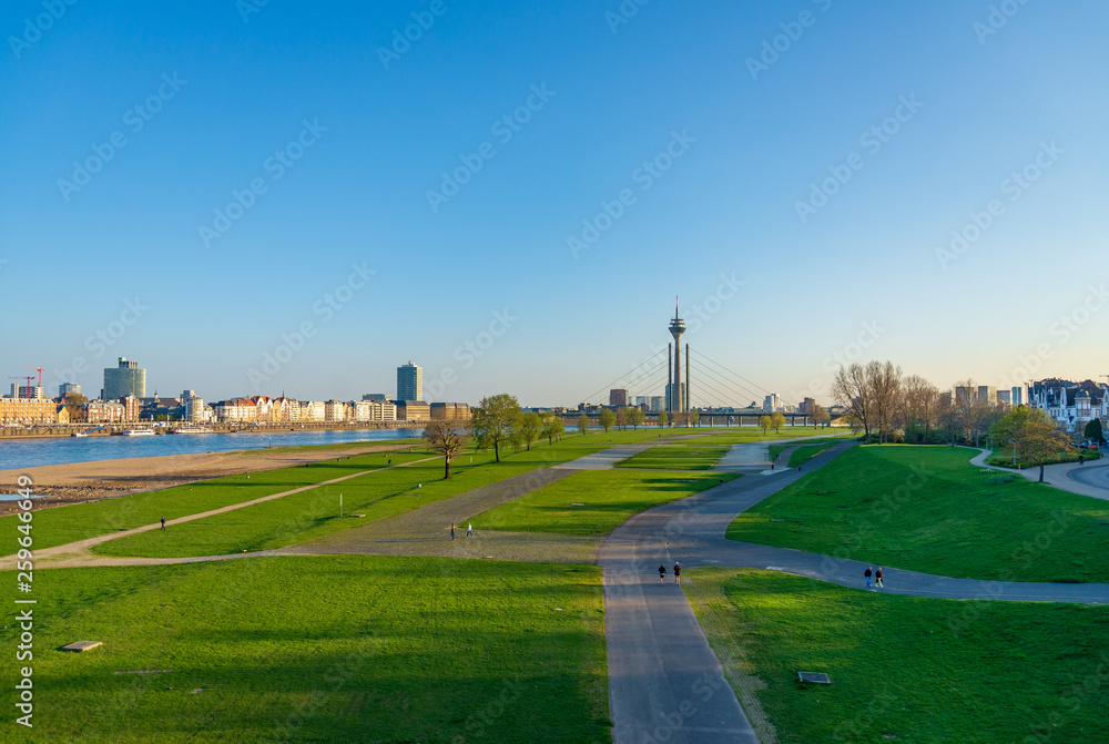 Aerial outdoor panoramic sunny scenic landscape view of natural promenade and green field on riverside of Rhine River, and background of skyline  cityscape Düsseldorf city,