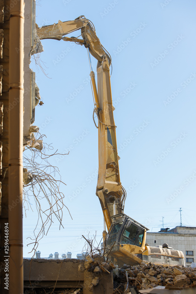 Obraz premium Closeup of destruction of building with hydraulic excavator/cutter crane. Reinforced concrete structures demolition