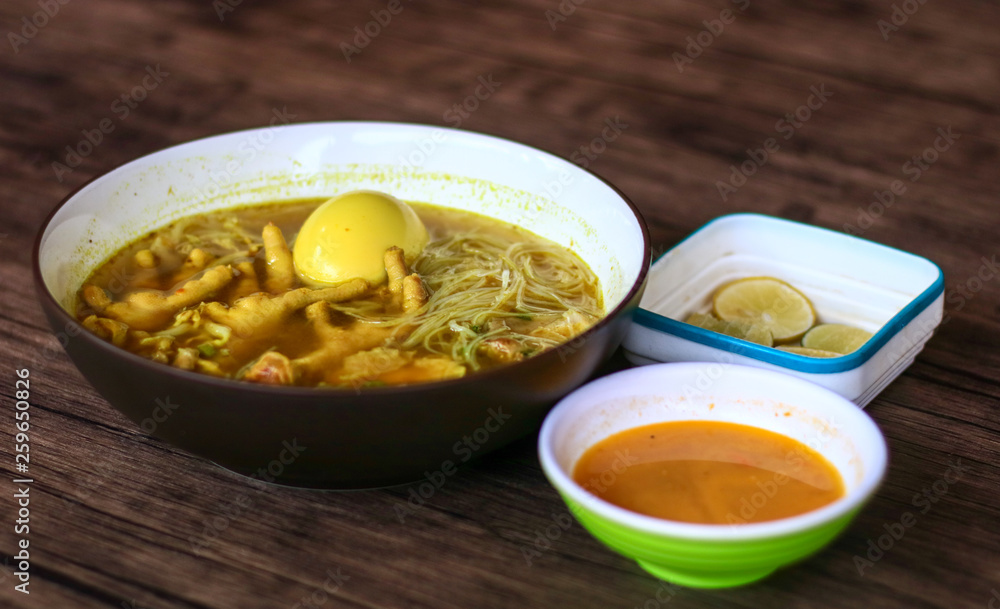 Soto ceker or chicken feet soup, chili sauce and lime on wood background. Soto ceker or chicken feet soup, chili sauce and lime on wood background.