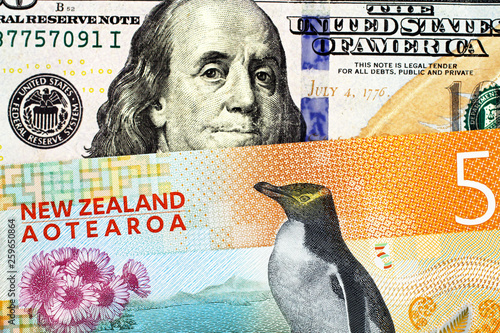 A close up image of an orange five dollar bill from New Zealand with a blue, new American one hundred dollar bill in macro photo