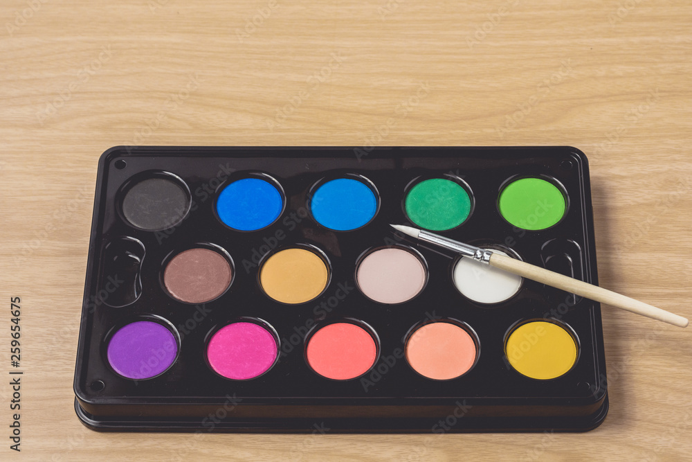 Paintbrush and Watercolor palette on brown wood table.using for Arts and Education background Paintbrush and Watercolor palette on brown wood table.using for Arts and Education background