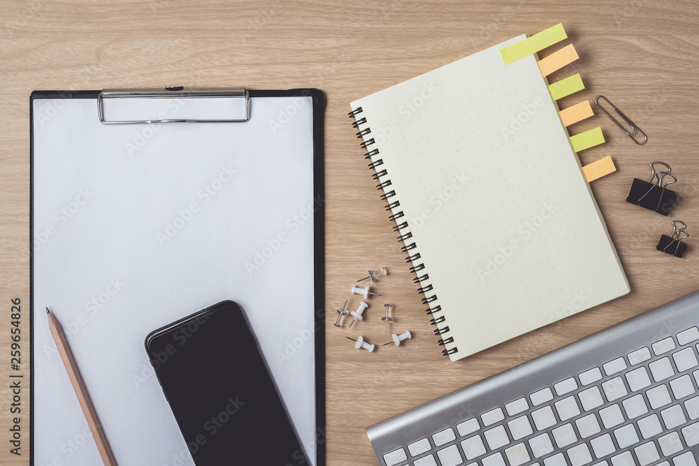 Workspace with diary or notebook and smart phone, clipboard, keyboard, pencil, sticky notes on wooden background Workspace with diary or notebook and smart phone, clipboard, keyboard, pencil, sticky notes on wooden background